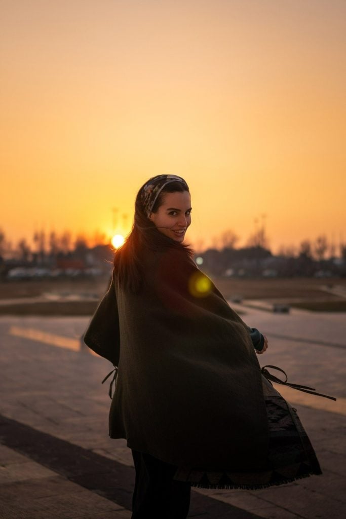Woman smiling looking back at camera with sunset behind her